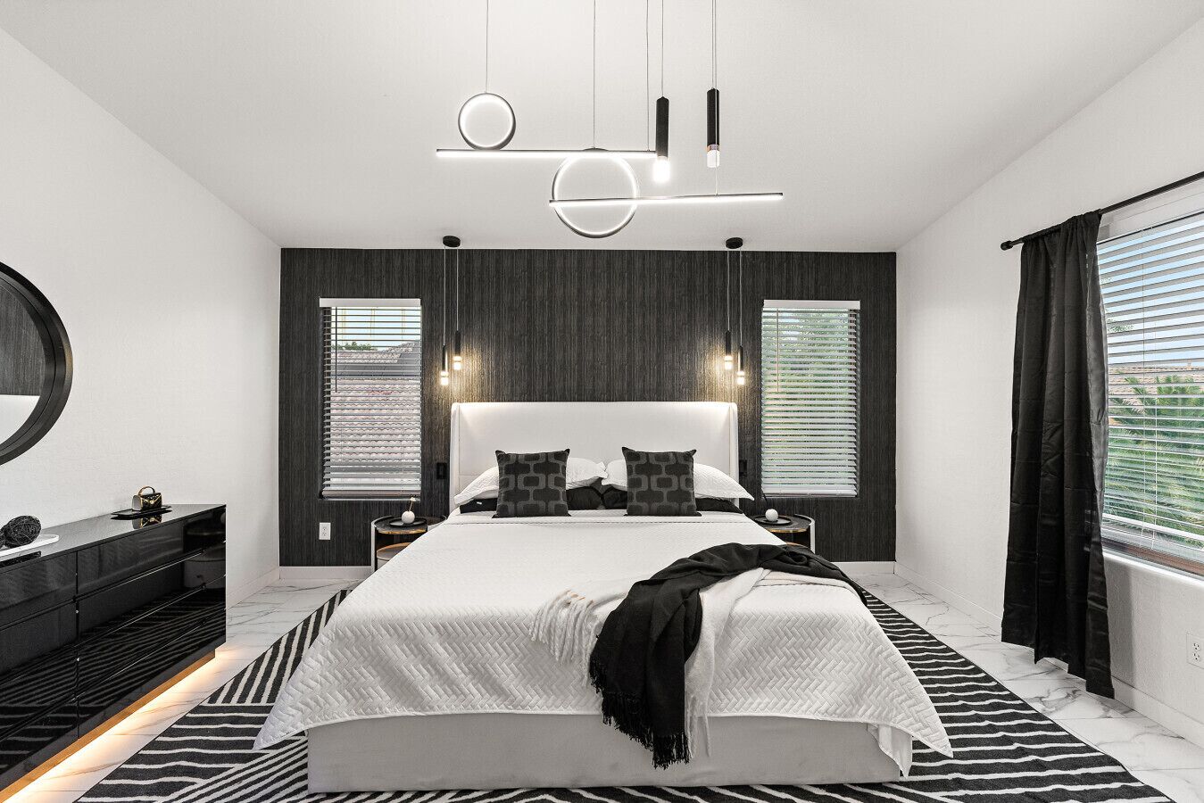 Ein modernes Schlafzimmer mit einem großen Bett, dunklen Holzpaneelen, einem runden Spiegel und einem schwarz-weißen Streifen Teppich.