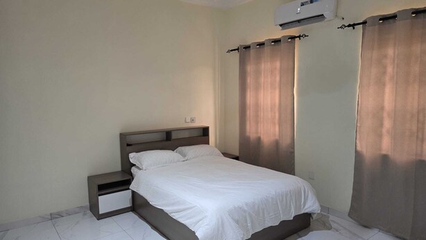 Un dormitorio con cama, mesita de noche y equipo de aire acondicionado.