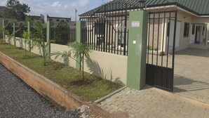 Un conjunto residencial cerrado con un edificio de techo verde, un camino pavimentado y un pequeño césped con árboles jóvenes.