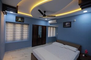 A bedroom with a bed, ceiling fan, and air conditioning unit. - VIKAS LUXURY STAY (Thiruvananthapuram)