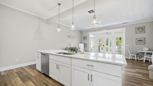 Een keuken met witte kasten, een roestvrijstalen vaatwasser en hanglampen.