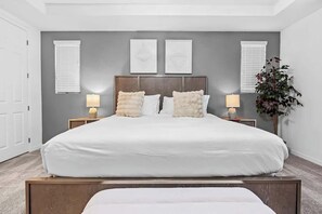 A bedroom with a large bed, two bedside tables with lamps, a headboard, and a plant. - Resort Home with Pool & Spa, Game Room, Near Disney (Kissimmee)