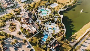 An aerial view of a resort with multiple swimming pools, a large central pool, and a heart-shaped pool. - Resort Home with Pool & Spa, Game Room, Near Disney (Kissimmee)