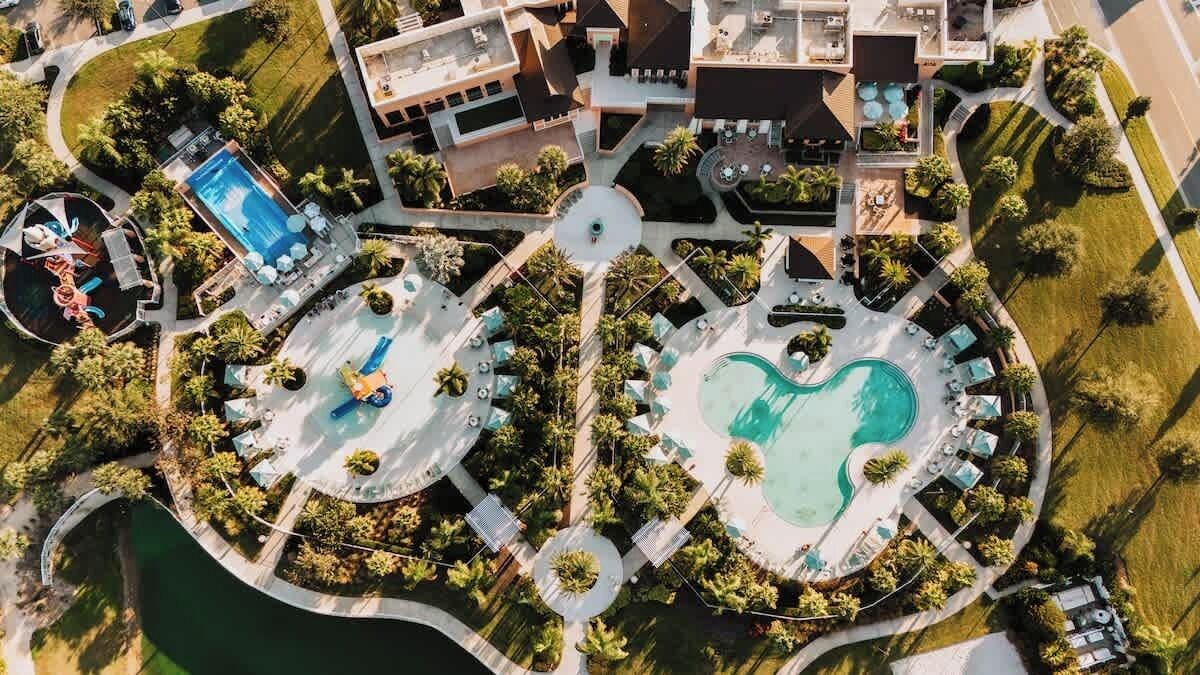 Eine Luftaufnahme eines Resorts mit mehreren Schwimmbecken, Palmen und Liegebereichen.