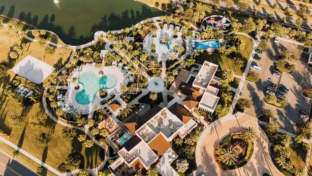 An aerial view of a resort with multiple swimming pools, a central circular area, and surrounding buildings. - Resort Home with Pool and Spa, Game Room, Near Disney (Kissimmee)