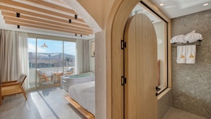Ein modernes Hotelzimmer mit Balkon, einer großen Holztür und Blick auf die Berge.
