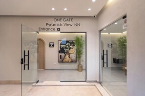 A hotel entrance with a glass door, a sign indicating 'ONE GATE Pyramids View NN', and a framed artwork above the door. - ONE GATE Pyramids View INN (Giza)