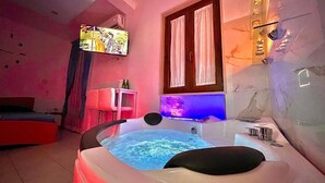 Ein Zimmer mit einer großen Whirlwanne, einem Fernseher und einem fenster mit Vorhängen.