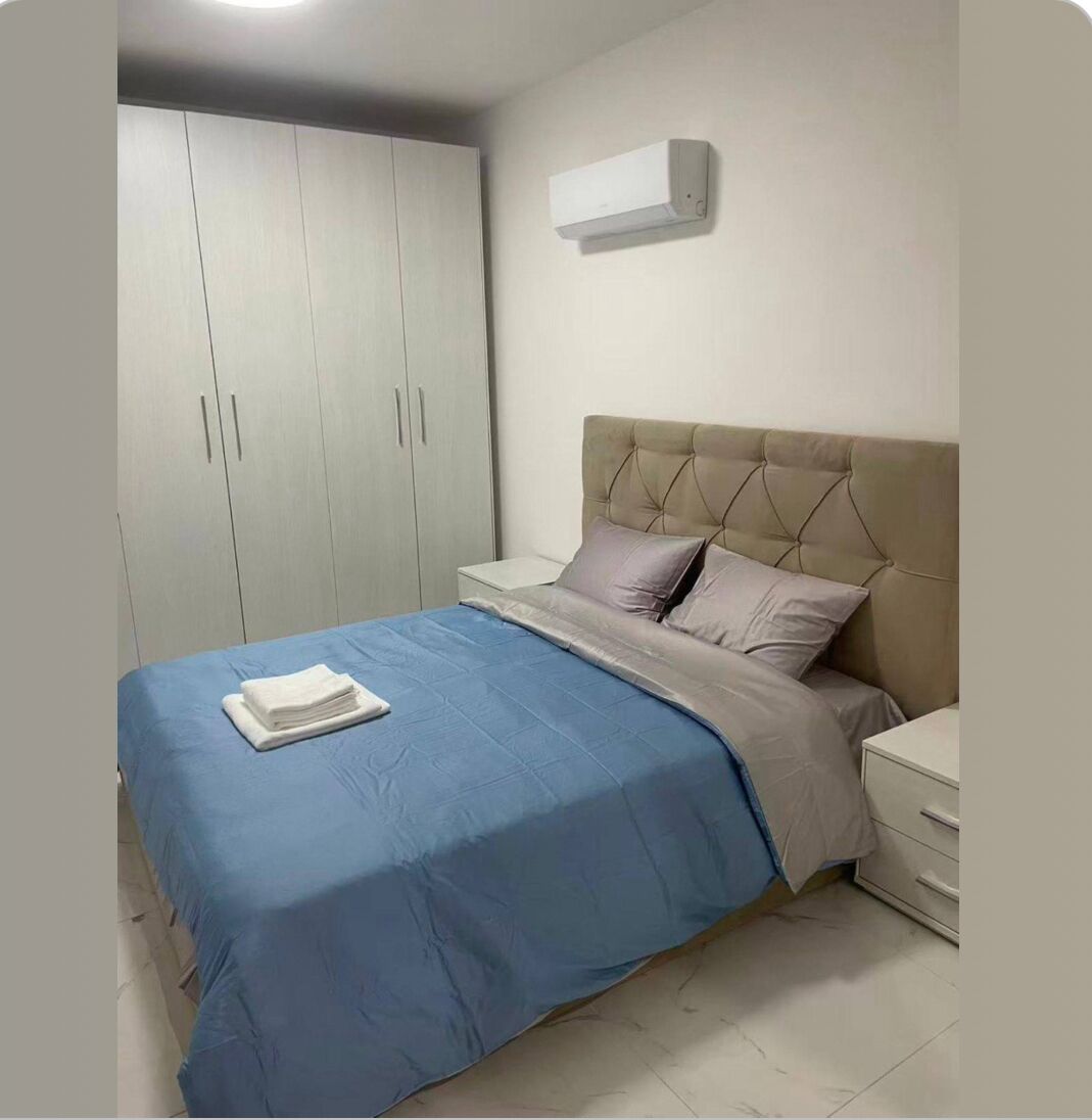 Ein Schlafzimmer mit Bett, Nachttisch, Kleiderschrank und Klimaanlage.