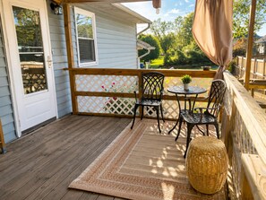 A wooden deck with a table and chairs, a wicker basket, and a view of a garden. - Modern Halethorpe Home. Sleeps 8. 4 Beds. Near BWI, UMBC & Baltimore (halethrope)
