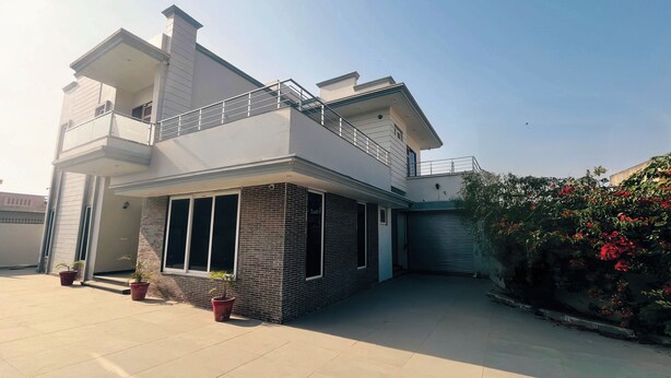 A modern two-story house with a balcony, a garage, and potted plants. - Sant Niwas Shahpur 3BHK Villa (Mohali)