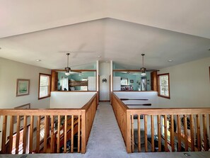 A spacious room with a high ceiling, wooden railings, and a central staircase. - Waterfront Home w/ Views from Every Room – Wake Up to Bay Sunrises! Pet Friendly (Port Haywood)