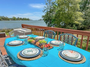 A table set for a meal with a view of a lake, surrounded by chairs and a railing. - Waterfront Home w/ Views from Every Room – Wake Up to Bay Sunrises! Pet Friendly (Port Haywood)