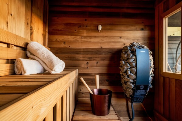 Een houten sauna met banken, een emmer en een sauna-oven.