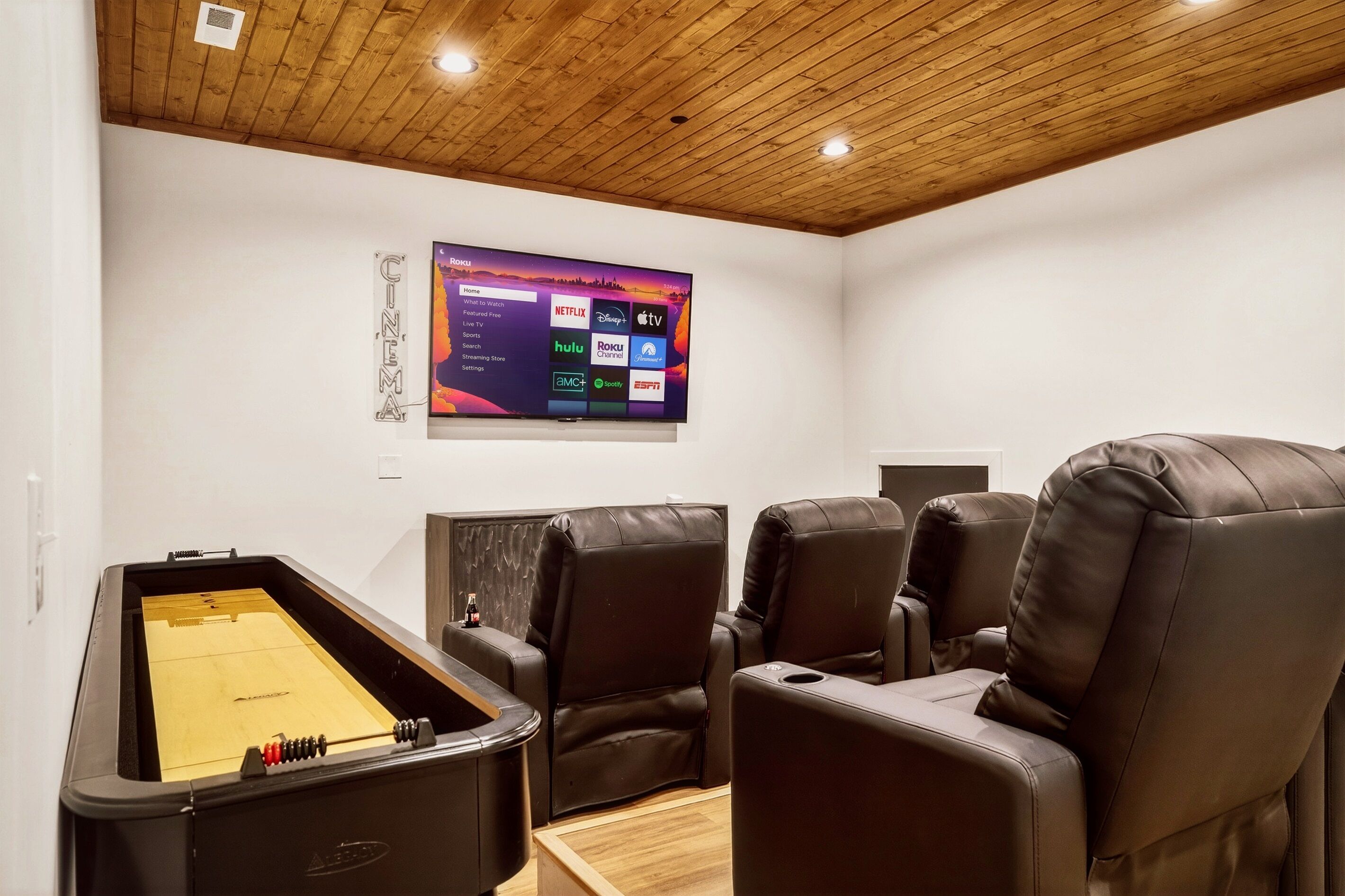 A room with a foosball table, reclining chairs, and a mounted TV displaying streaming services.