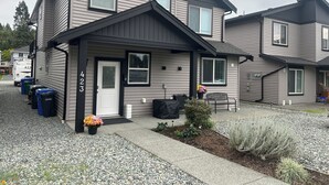 A two-story residential building with a front porch, a mailbox, and a small garden area with gravel and plants. - Stay at Silver Mountain Drive (Nanaimo)
