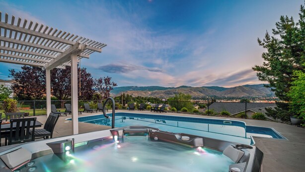 Un jacuzzi con vistas a las montañas y un área de piscina con sillones de descanso.