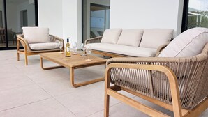 A modern outdoor seating area with wicker furniture and a wooden coffee table.