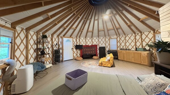A yurt interior with a sofa, a small table, a TV, and a kitchen area.