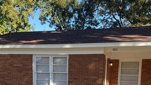 A brick house with a number '1012' on the side, a front porch, and a gravel driveway. - Cozy 1-bedroom home in the heart of Jonesboro! (Jonesboro)
