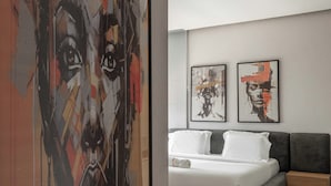 A modern bedroom with a large abstract painting, a bed with gray bedding, and two smaller artworks on the wall. - Coral Luxe Suite - Spacious  Luxury 3 Bed Waterfront View in quiet VI cul-de-sac (Lagos)