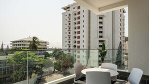 A balcony with a glass railing, white chairs, and a small table. - Coral Luxe Suite - Spacious  Luxury 3 Bed Waterfront View in quiet VI cul-de-sac (Lagos)