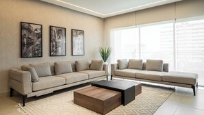 A modern living room with a sofa set, a coffee table, and three framed artworks on the wall. - Coral Luxe Suite - Spacious  Luxury 3 Bed Waterfront View in quiet VI cul-de-sac (Lagos)