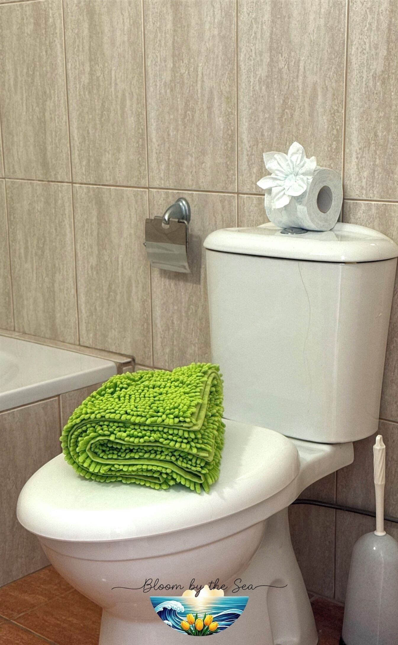 Un inodoro con una toalla verde sobre el asiento y un dispensador de papel higiénico con un rollo.