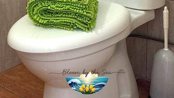 Un inodoro con una toalla verde sobre el asiento y un dispensador de papel higiénico con un rollo.