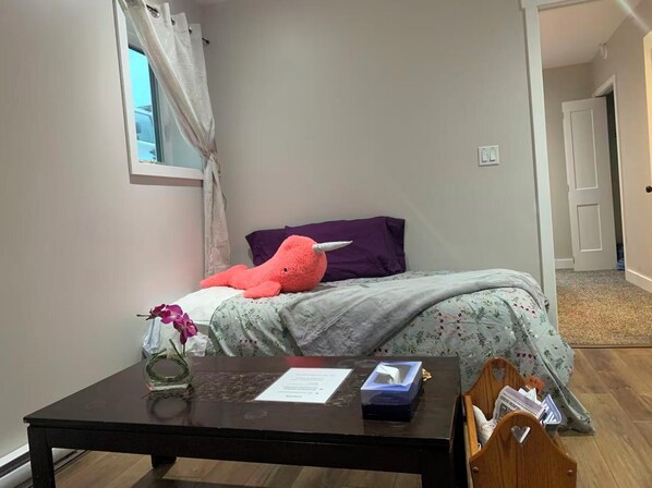 Une chambre à coucher avec un lit, un bureau, une chaise, une fenêtre avec des rideaux et une porte.