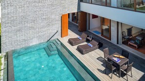 Ein moderner Poolbereich im Freien mit Liegestühlen und einem Esstisch.