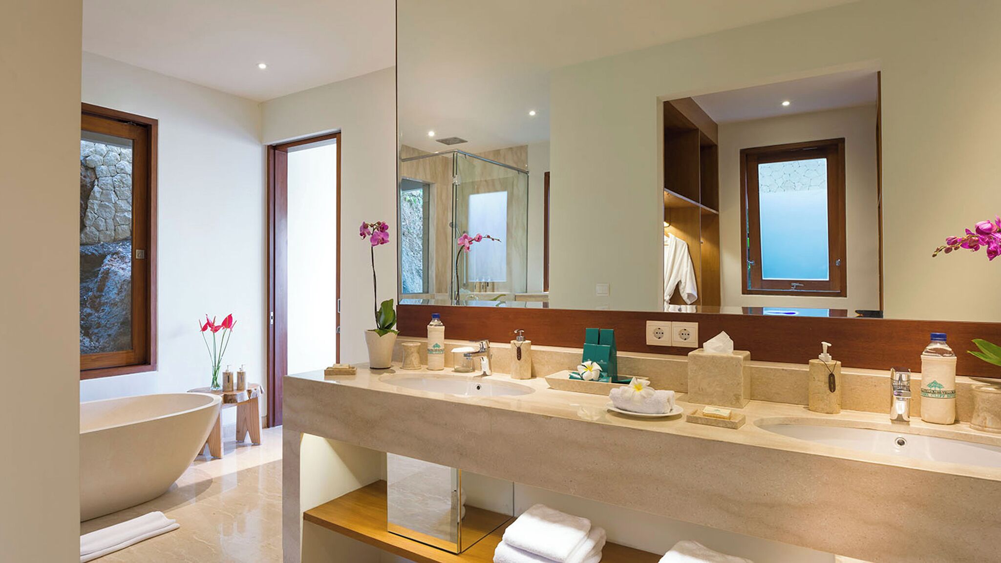 Ein modernes Badezimmer mit einem großen Spiegel, zwei Waschbecken, einer Badewanne und einer Duschkabine.