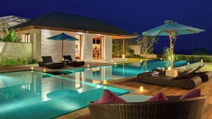 Ein modernes Haus mit Schwimmbad, Sitzgelegenheiten im Freien und einer überdachten Terrasse.