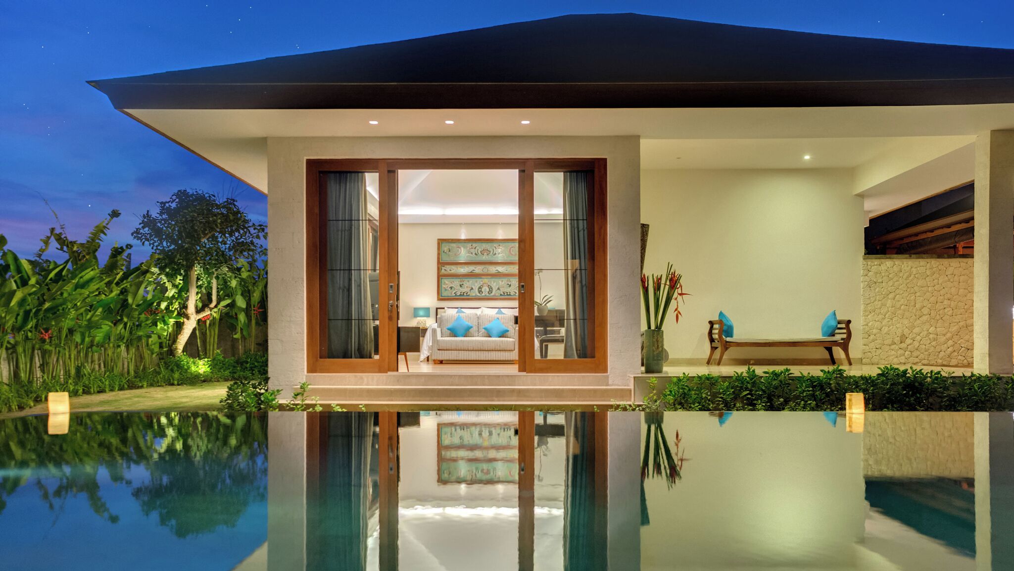 Une maison moderne avec une piscine, un canapé et un fauteuil dans le salon.
