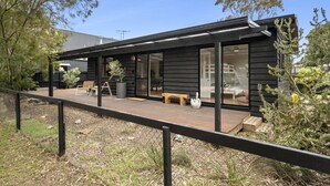 Ein modernes Haus mit Terrasse, großen Fenstern und Sitzgelegenheit im Freien.