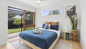 Ein Schlafzimmer mit einem großen Bett, einem Deckenventilator, einem Fenster und Blick auf den Garten.