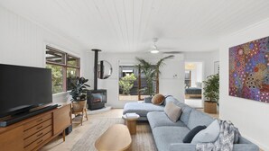 Ein modernes Wohnzimmer mit Flachbildfernseher, Kamin, einer Couch und einem großen Gemälde.