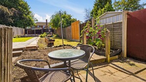 A backyard with a table and chairs, a wooden fence, and a garden. - 2 bed Home with Free Parking (Walsall)