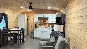 Una habitación compacta con paneles de madera, zona de comedor, asientos, kitchenette y ventilador de techo.