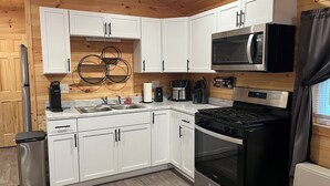 Una cocina moderna con armarios blancos, una estufa de acero inoxidable, un microondas y un fregadero.