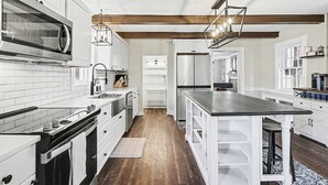 Una cocina moderna con armarios blancos, electrodomésticos de acero inoxidable y piso de madera.