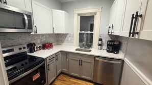 Una cocina moderna con electrodomésticos de acero inoxidable, armarios blancos y un salpicadero gris.