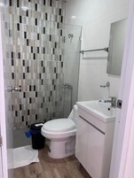 Un baño con ducha de azulejos, inodoro, lavabo y espejo.