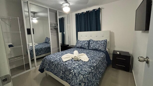 Een slaapkamer met een bed, nachtkastje, spiegel en kledingkast.