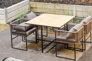Une terrasse extérieure avec une table carrée et quatre chaises.