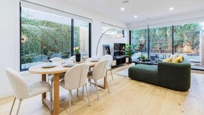 Ein modernes Interieur mit Essbereich, Sofa und großen Fenstern.