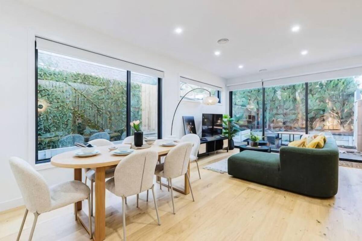 Un interior moderno con zona de comedor, sofá y ventanas amplias.