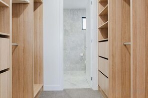 Un couloir avec des étagères en bois et une porte donnant accès à une salle de bain.