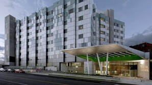 Ein modernes Hotel mit Glasfassade, überdachter Eingangspartei und sichtbarem Parkbereich.