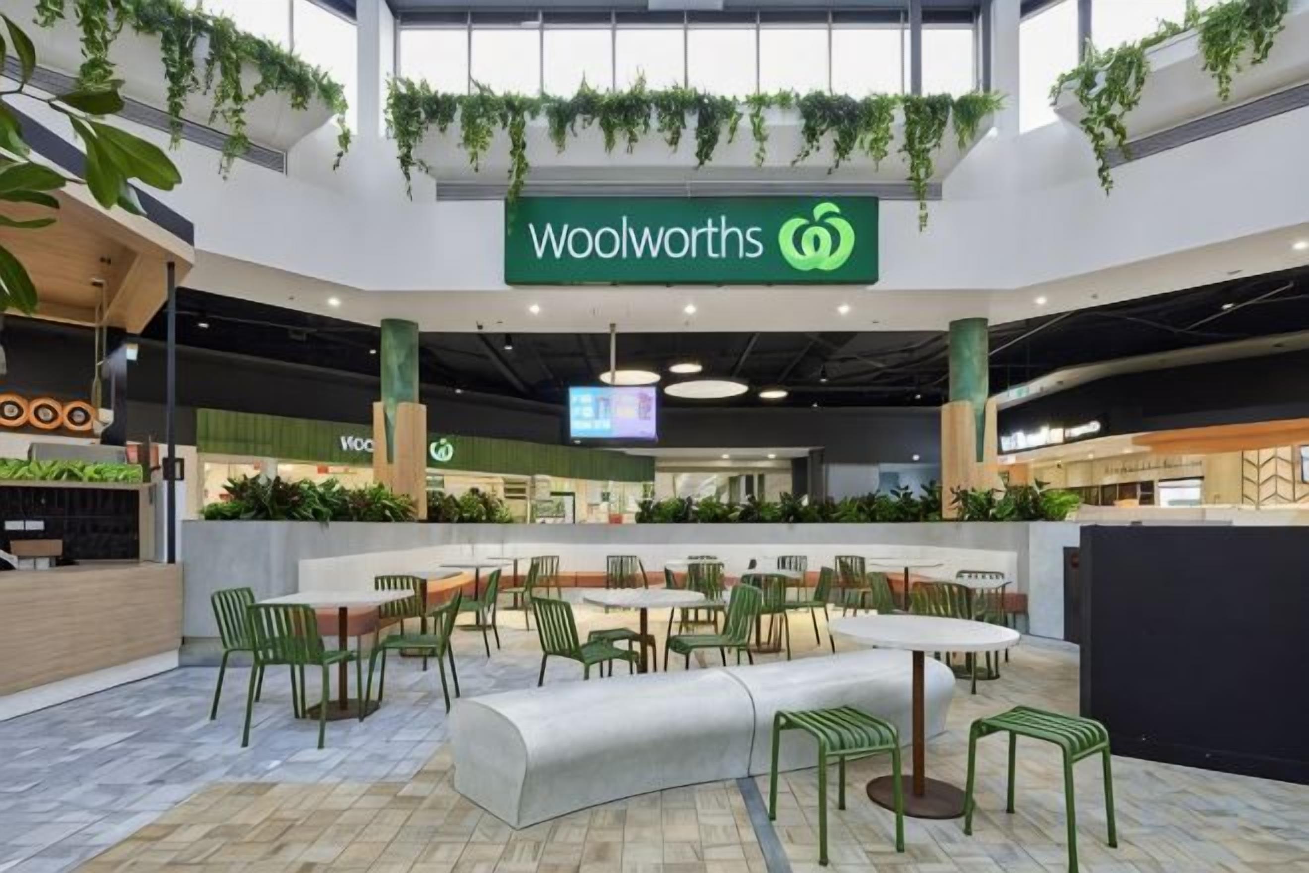 A Woolworths supermarket with a central seating area, surrounded by greenery and a modern interior design.